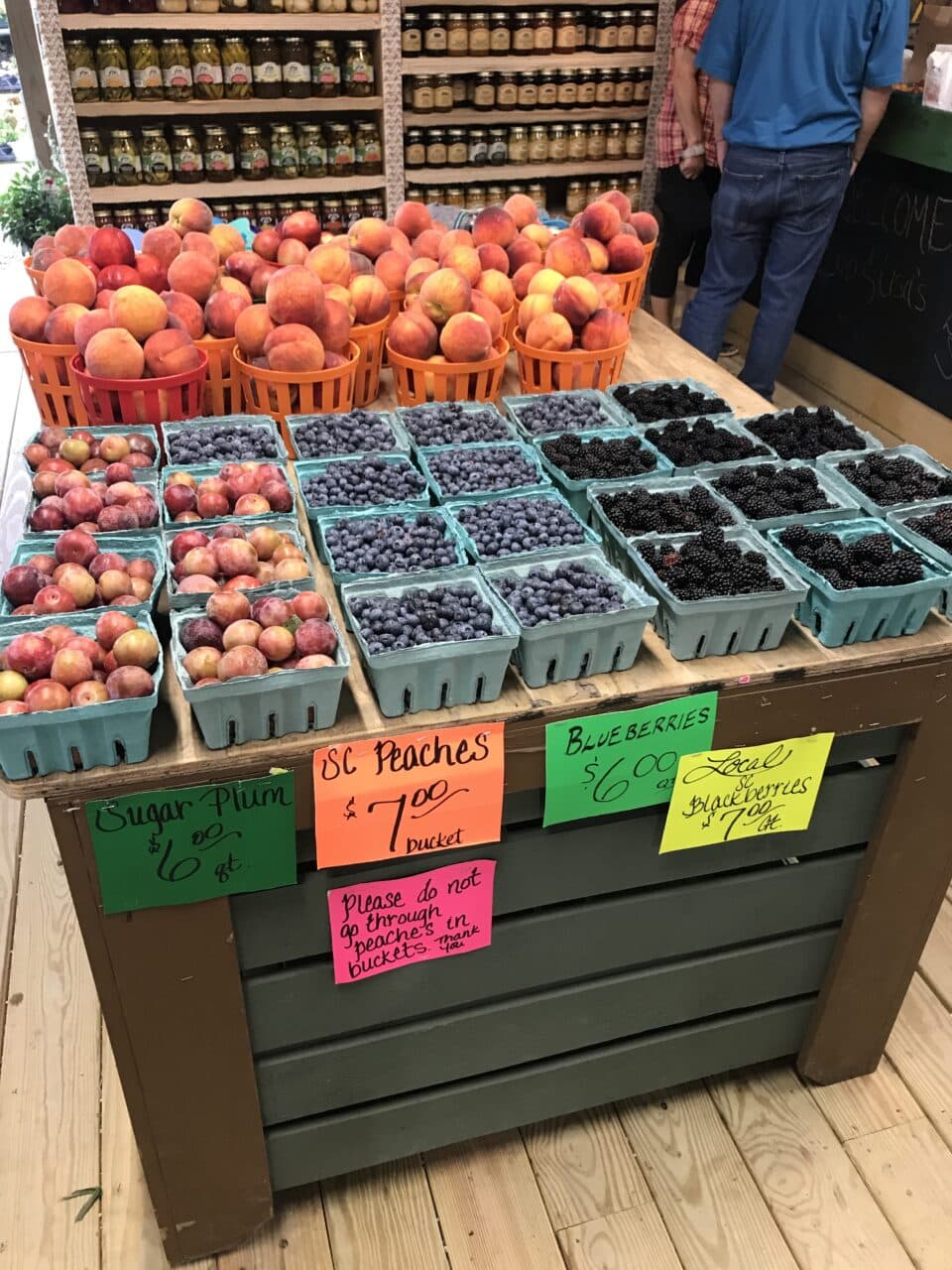 a fruit stand with peaches, blueberries, and blackberries